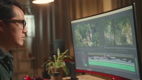 tired asian male video editor works with footage and sound on his personal computer, he works late at night