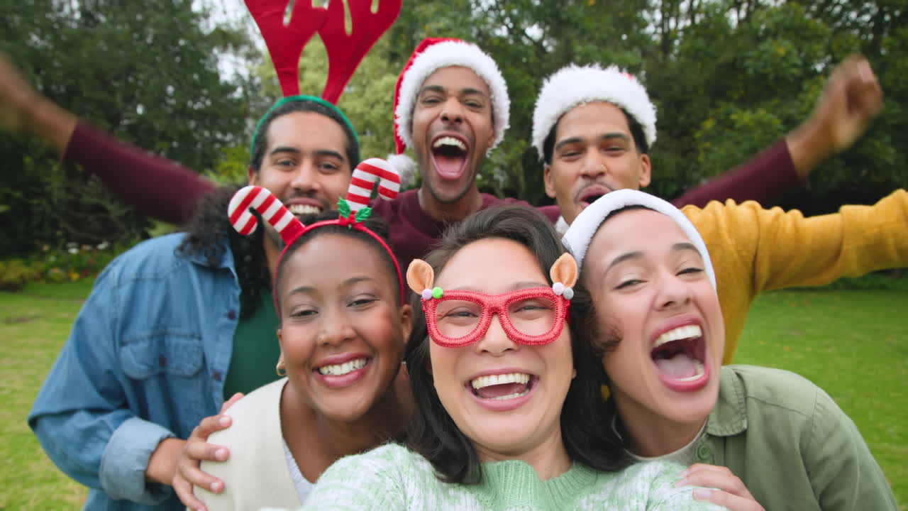 Celebrating Christmas outdoors, diverse friends wearing festive hats smiling joyfully together
