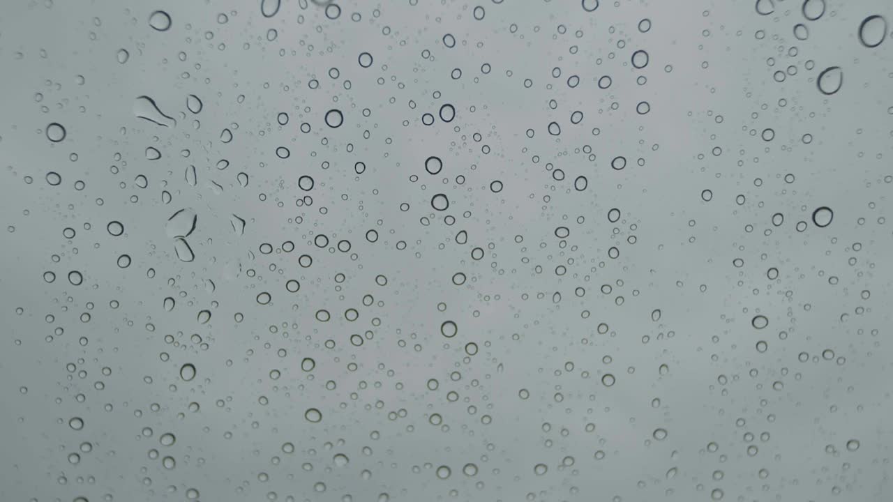gotas de lluvia abstractas en el parabrisas del coche a cámara lenta
