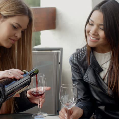 friend pouring woman wine at table