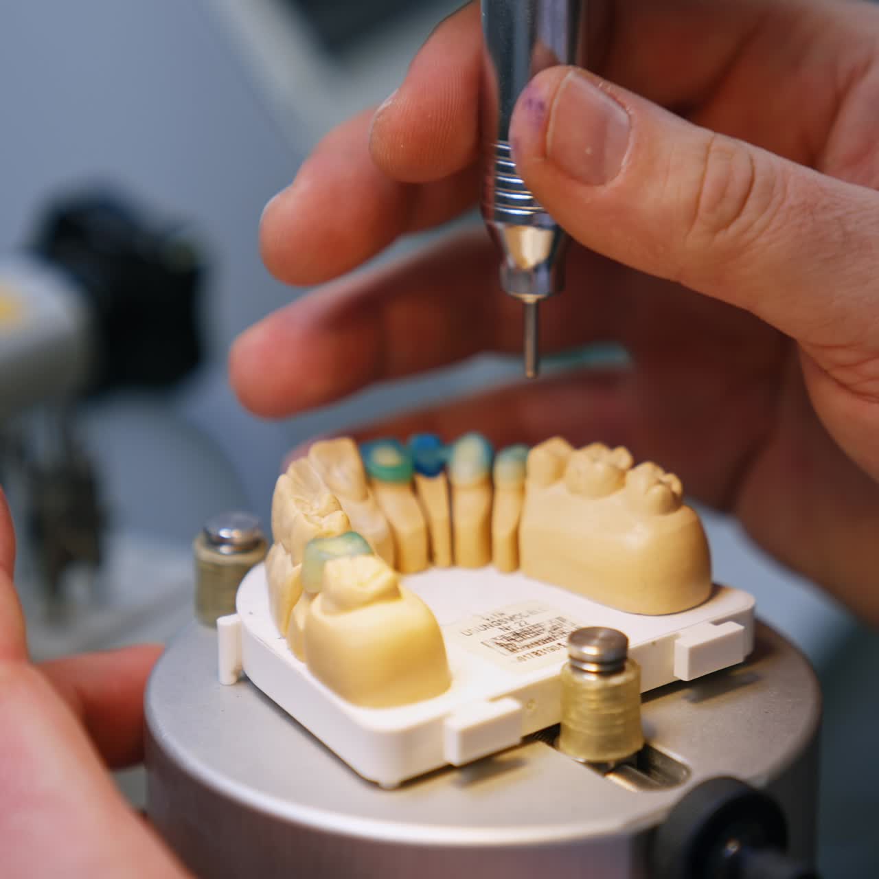 Manufacturing the model of denture. Close up. Technician's hands operating the machine tool for denture production