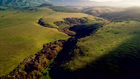 dawn sun streams over california mountains to light rolling green hills