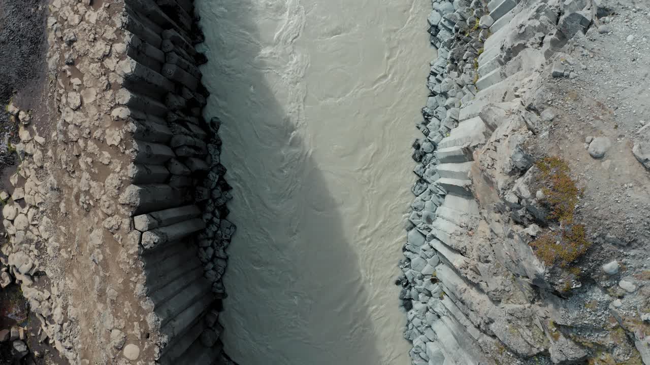 el elevador de arriba hacia abajo del dron revela columnas de basalto, río glacial - studlagil, islandia