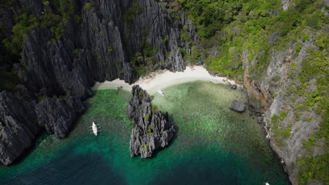 boats pull ashore on an isolated beach surrounded by steep cliffs on tropical island