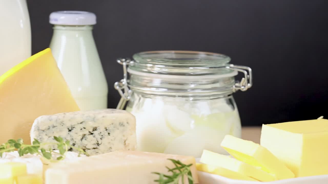 A variety of dairy items including milk, cheese, and yogurt displayed on a wooden table.