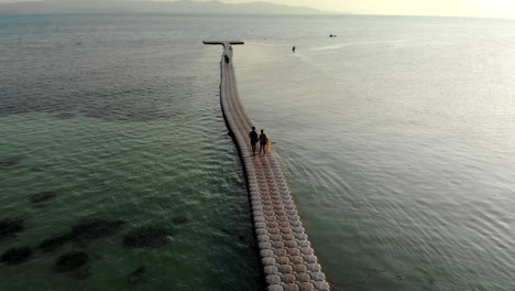 Drohnenaufnahme-Eines-Paares,-Das-Auf-Einem-Schwimmenden-Pier-Spazieren-Geht