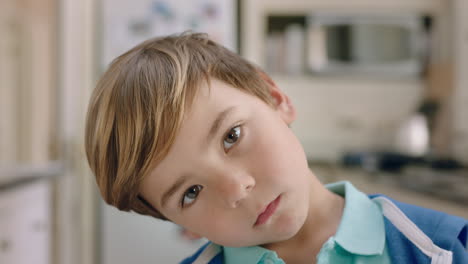 portrait happy little boy looking at camera with curious expression cute child at home in kitchen