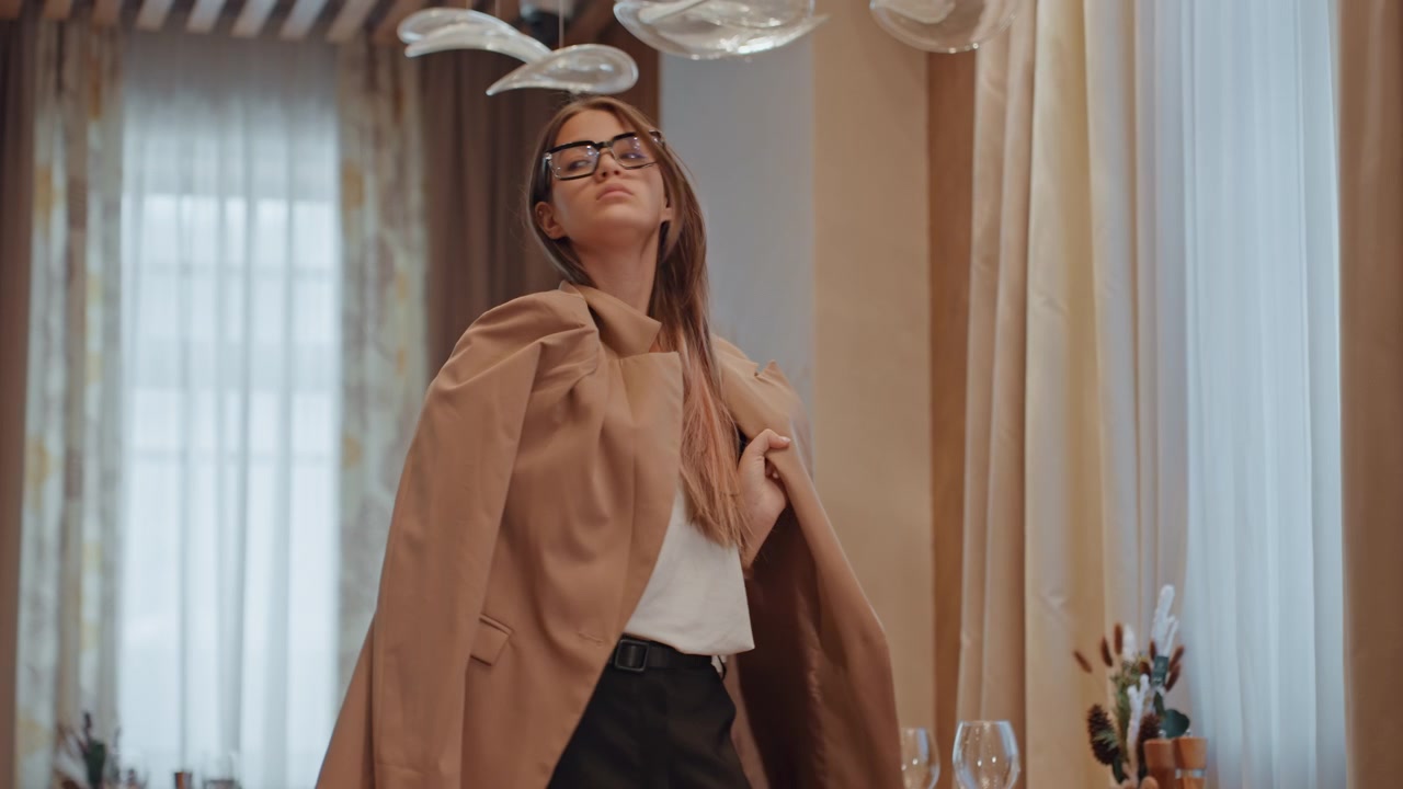 Mujer blanca en una mesa de comedor se pone el abrigo y se levanta para irse, en un interior de restaurante elegante, con iluminación cálida, cristalería y cortinas, mostrando una postura segura, atuendo de negocios y movimiento hacia la salida.