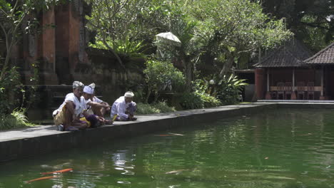 Balinese men sitting around at a temple pond
