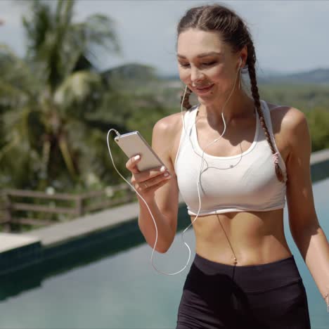 deportista sonriente escuchando música cerca de la piscina