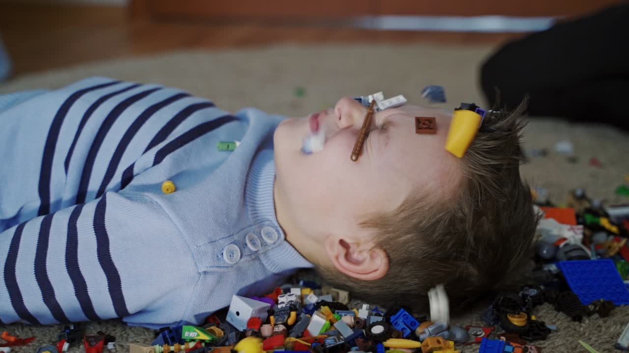 The child plays with colorful plastic toy blocks. Educational toys for young children. Mess in play room. Slow motion