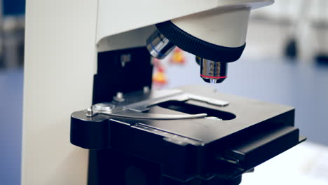 un profesor universitario que prepara diapositivas de células cancerosas humanas para un microscopio para mostrar a sus estudiantes en un laboratorio de investigación de biología médica
