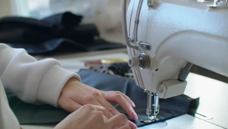 sewing machine needle in motion. close-up of sewing machine needle rapidly moves up and down. the tailor sews black fabric on the sewing workshop. the process of sewing fabric.
