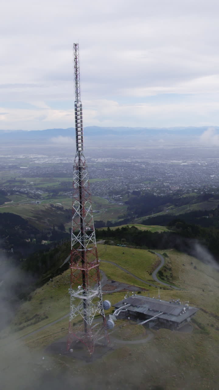 Vertical drone shot passing the Sugarloaf mountain tower, misty day in NZ