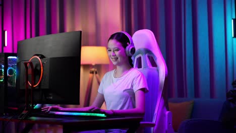 una adolescente asiática emocionada celebra la victoria y baila mientras juega videojuegos en la computadora