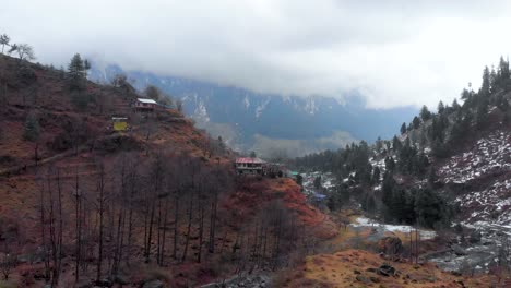 aerial parallax reveal shot of old-manali town with light snowfall showers near the manalsu river front in himachal pradesh shot with a drone in 4k