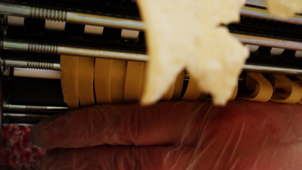 Fresh Pasta Dough Being Cut into Noodles by a Pasta Maker