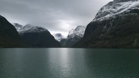 Majestic-Lake-Lovatnet-in-Norway-with-snowy-mountains-and-cloudy-skies,-tranquil-nature-scene