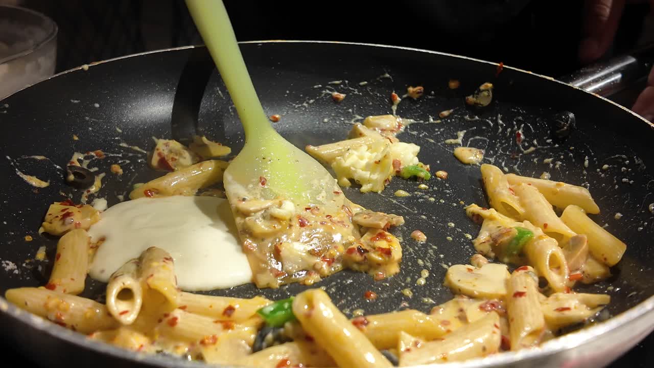 Cooking Penne Pasta with Creamy Sauce and Chili Flakes in a Frying Pan