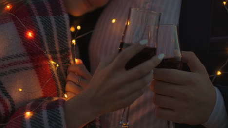 close-up hands holding glasses of wine at sunset. strong romantic feelings. sunset date on the roof.