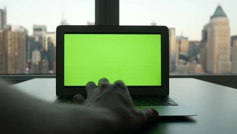 portátil de negocios con pantalla verde monitor de clave croma y fondo de paisaje urbano.