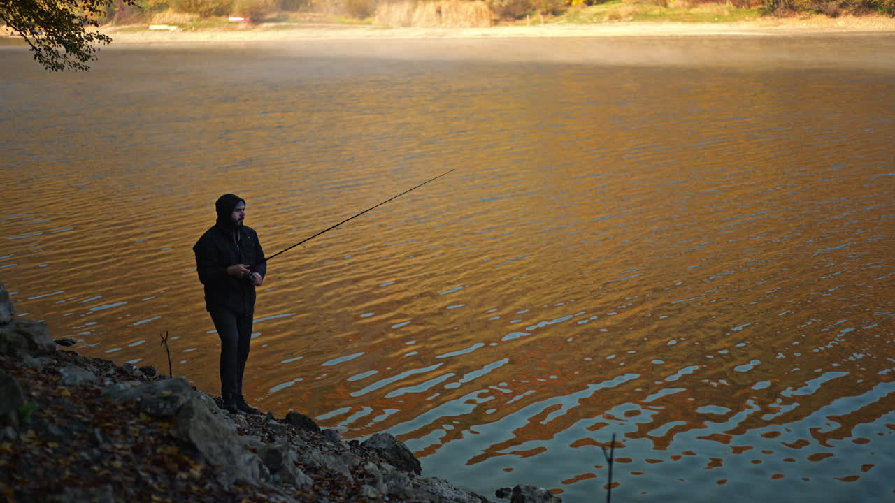Pria memancing di danau yang tenang pada musim gugur