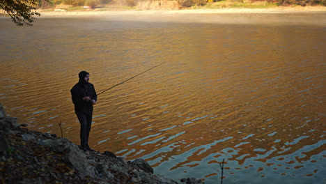 man fishing on a calm lake in autumn