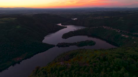 aerial shot revealing the loire river in the gorges de la loire with the plateau de la danse viewpoint in the foregound at sunset, loire departement, auvergne rhone alpes region, france