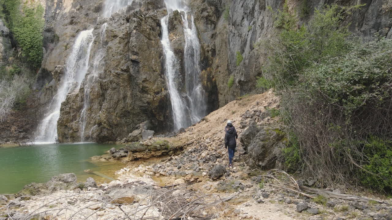 Aerial view of waterfall in the middle of the mountain.  People discovering a nature landscape.