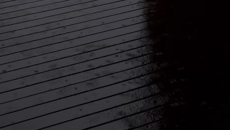 Gotas-De-Lluvia-Golpeando-Una-Terraza-De-Madera-Oscura-Por-La-Noche