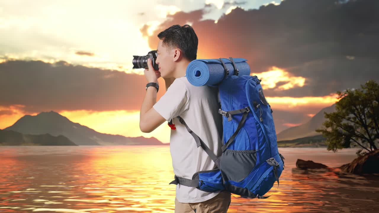 Side View Of Asian Male Hiker With Mountaineering Backpack Using A Camera Taking Picture At A Lake