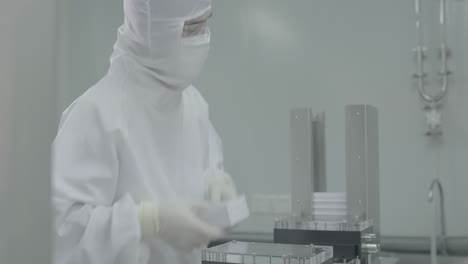 pharmaceutical packaging line facility, medical workers equipped with protective suits, face masks and safety goggles are meticulously placing medication into packaging, ensuring safety and accuracy