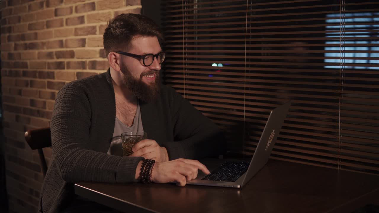 hombre trabajando en una computadora portátil en un bar por la noche