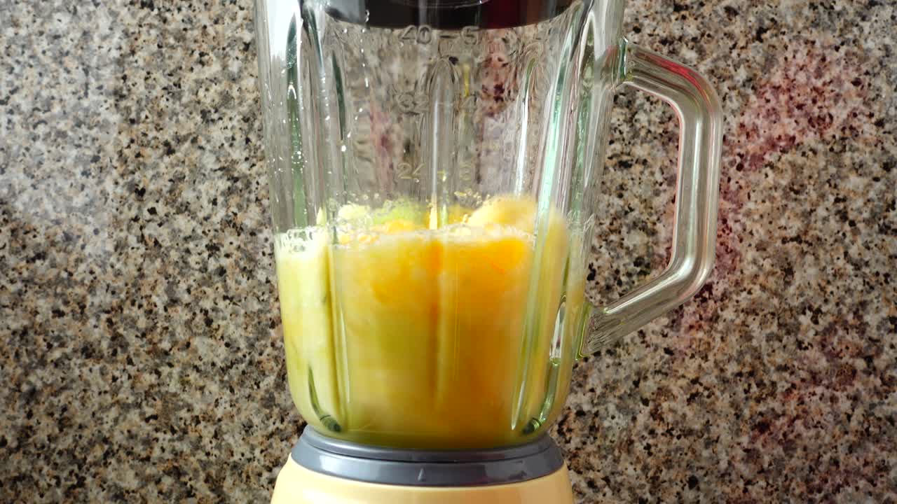 Colocando no liquidificador um kiwi, laranjas e bananas. Preparação de smoothie no liquidificador.