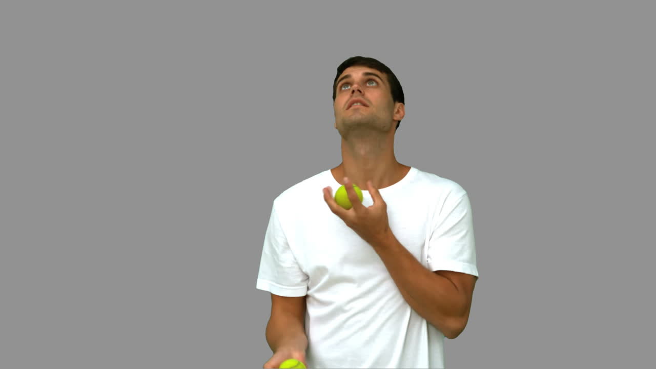 hombre guapo driblando con bolas en la pantalla gris