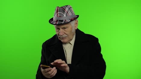 anciano elegante abuelo caucásico usando una aplicación de redes sociales en su teléfono inteligente
