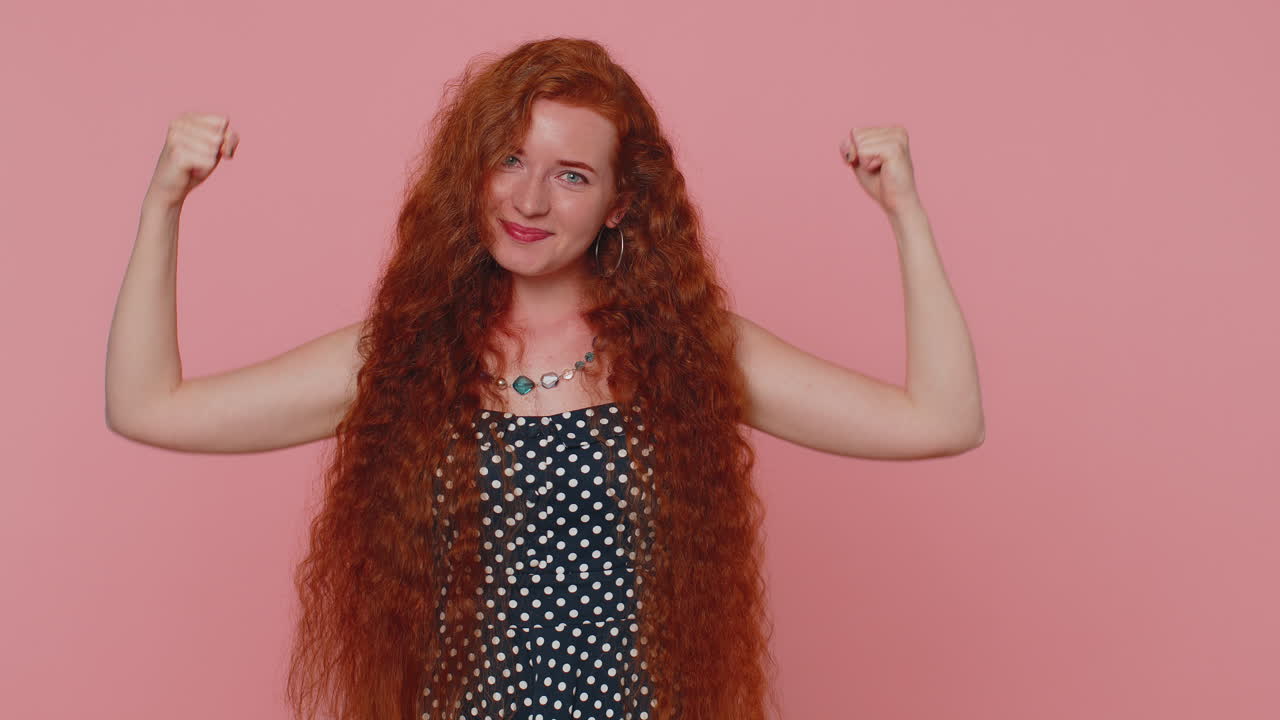 mujer roja deportiva en forma mostrando bíceps y pareciendo segura, sintiendo poder fuerza éxito ganar