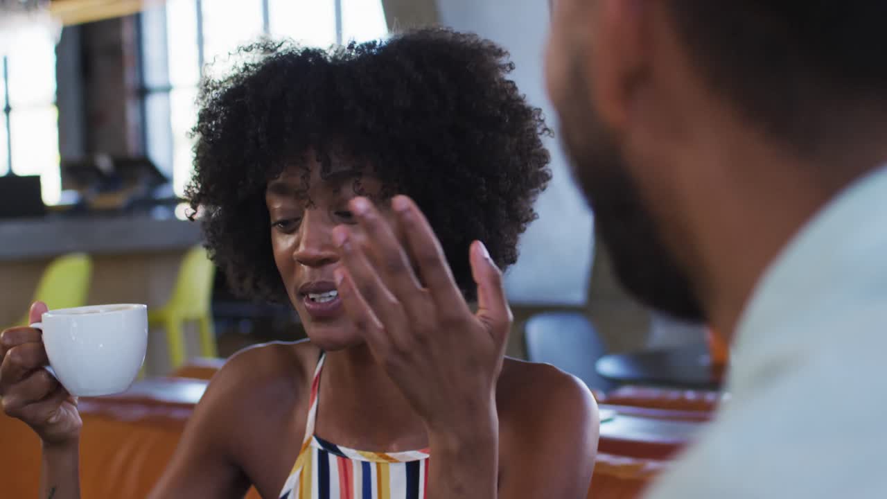 diversos colegas masculinos y femeninos sentados en una cafetería bebiendo café teniendo una discusión