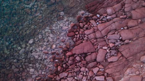 vista aérea aérea del agua turquesa por piedras rojas, espiral alejándose