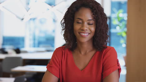 portrait of smiling businesswoman working at desk in modern open plan office