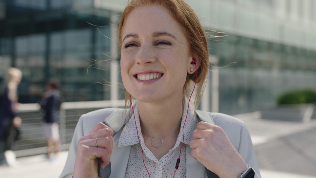 retrato de cerca de una atractiva mujer de negocios de cabello rojo, una interna sonriente, una animadora con auriculares, disfrutando de su nueva carrera corporativa en la ciudad.