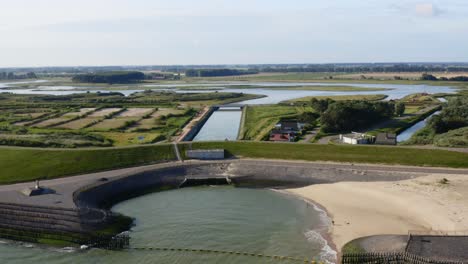 Aerial-approach-to-the-sea-dam-with-a-biker-in-a-nature-area-and-recreational-park-Waterdunen-in-the-province-of-Zeeland,-The-Netherlands