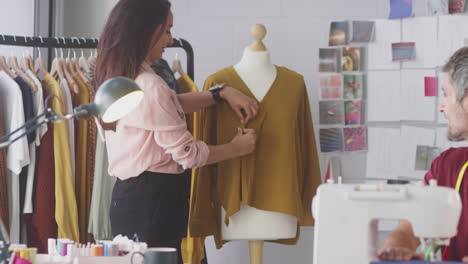 Diseñadores-De-Moda-Masculinos-Y-Femeninos-Sonrientes-Con-Máquina-De-Coser-Trabajando-Juntos-En-El-Estudio