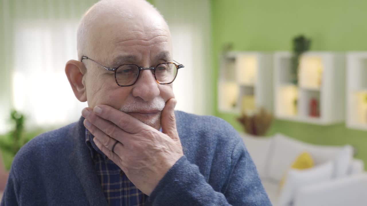 Worried thoughtful old adult man at home alone in front of mirror thinking about life.