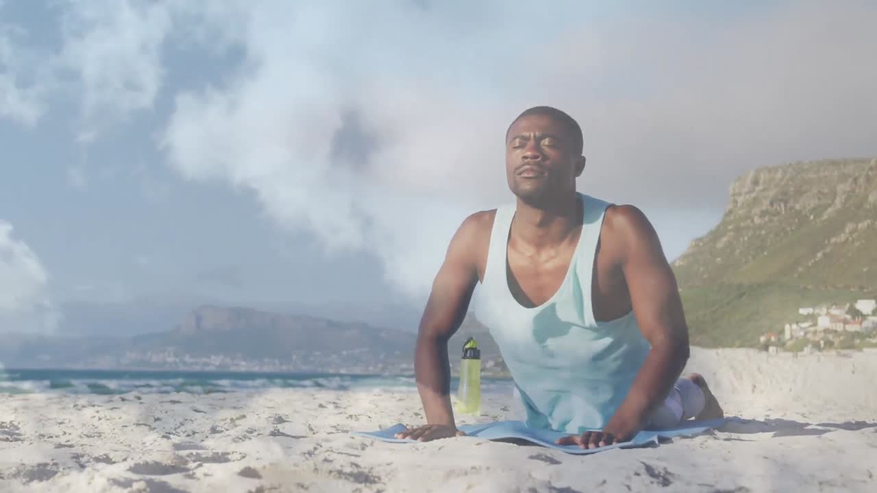 Sahilde kobra yoga pozu yapan Afro-Amerikalı adamın üzerinde bulut animasyonu