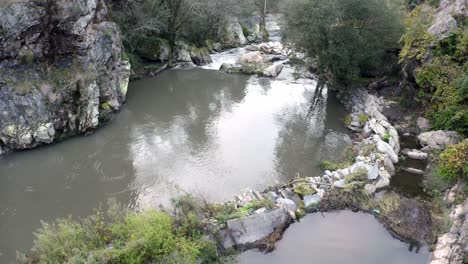 calm river water with reflections flowing through rocks in portugal - high angle shot