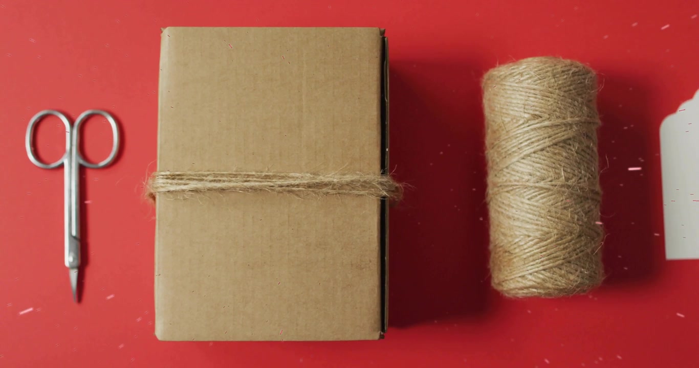 Flat-lay featuring spool sliding toward box starting gift tag entering and sprig completing wrap