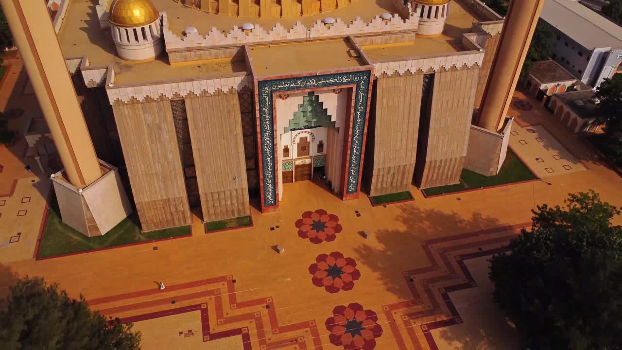 Top down aerial of the square in front of a beautiful mosque. The drone pulls back and reveals the stunning Abuja National Mosque in Nigeria, Africa