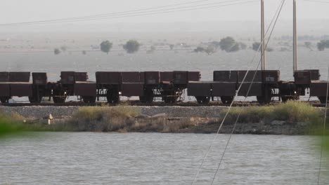 empty rail wagons on railway tracks with floodwaters either side in sindh