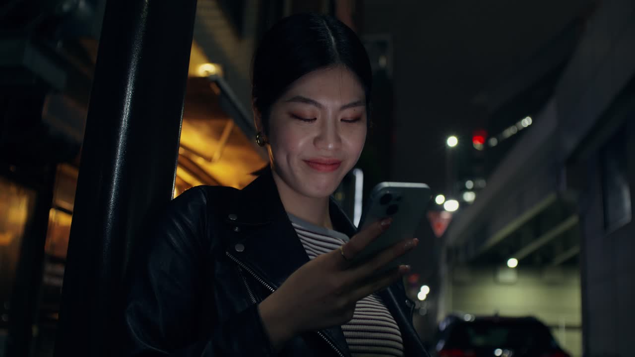 Woman using smartphone at night in city street
